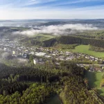 Aerial view shot of beautiful green fields and houses of the countryside on a sunny day Ein Blick in unser schönes Mustertal